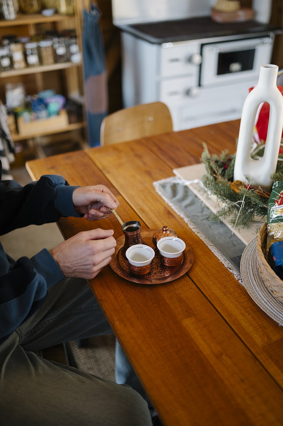 Two small coffee cups and a coffee pot on a shared wooden table