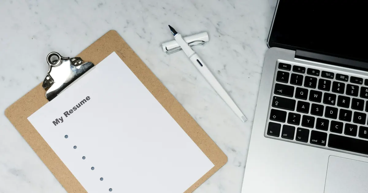 A resume document beside a laptop, ready for a review of application evidence.
