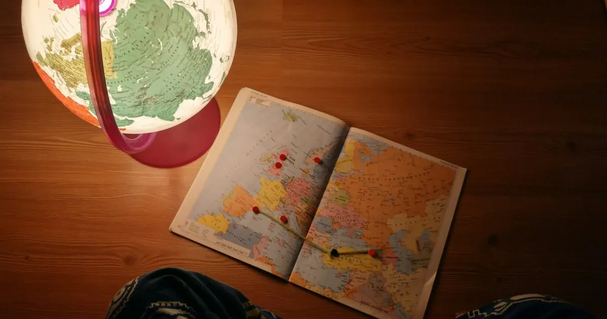 A world map and desk globe beside a notebook, illustrating location-based research.