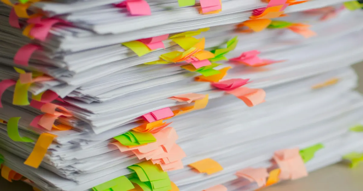 A stack of documents marked with colourful sticky tabs.