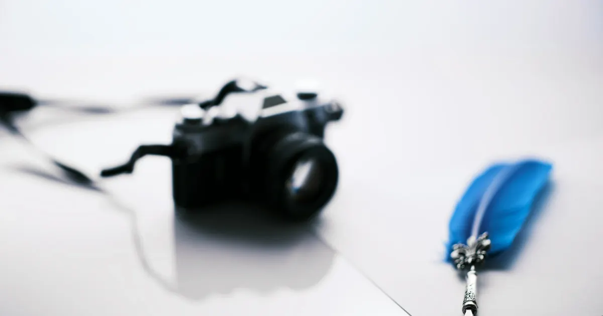A camera and writing pen on a white surface, representing reporting and communication.